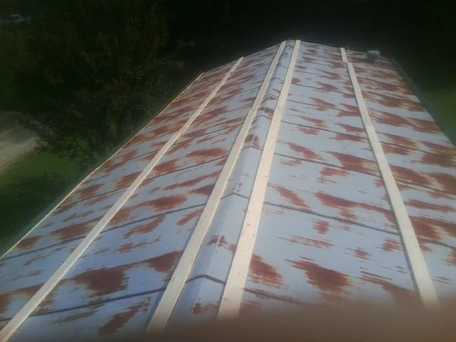 Rusted metal roof panels with new wood purlins before replacement — Storm Damage Roof Repair in East Liberty by Roofing Brothers