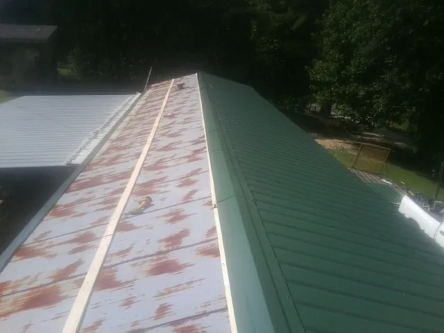 Old rusted panels beside newly installed green metal roofing — Wind Damage Roof Repair by Roofing Brothers in East Liberty