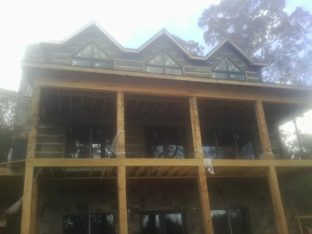 Dormers and porch framing on a large log home under construction — Roof Coating work by our crew in East Liberty