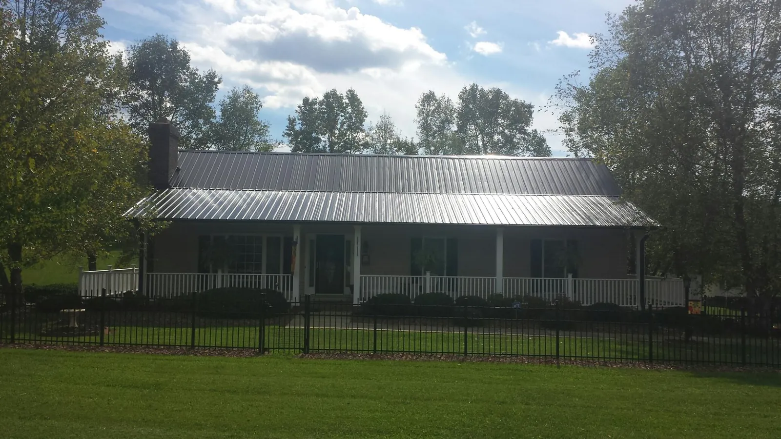 Gray metal roof on a brick ranch with a full width front porch — Gutter Guard Installation work by our crew in East Liberty
