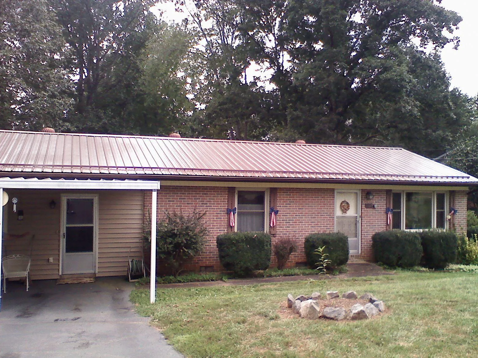 Bronze metal roof and carport on a brick ranch home — Roof Repair work by our crew in East Liberty
