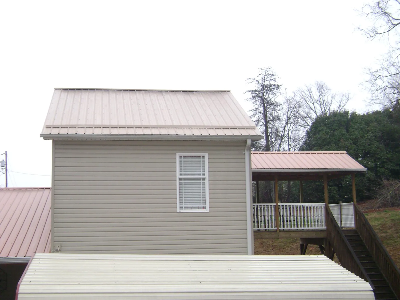 Tan metal roofs on a two story addition and attached porch, from a Roof Replacement job in East Liberty
