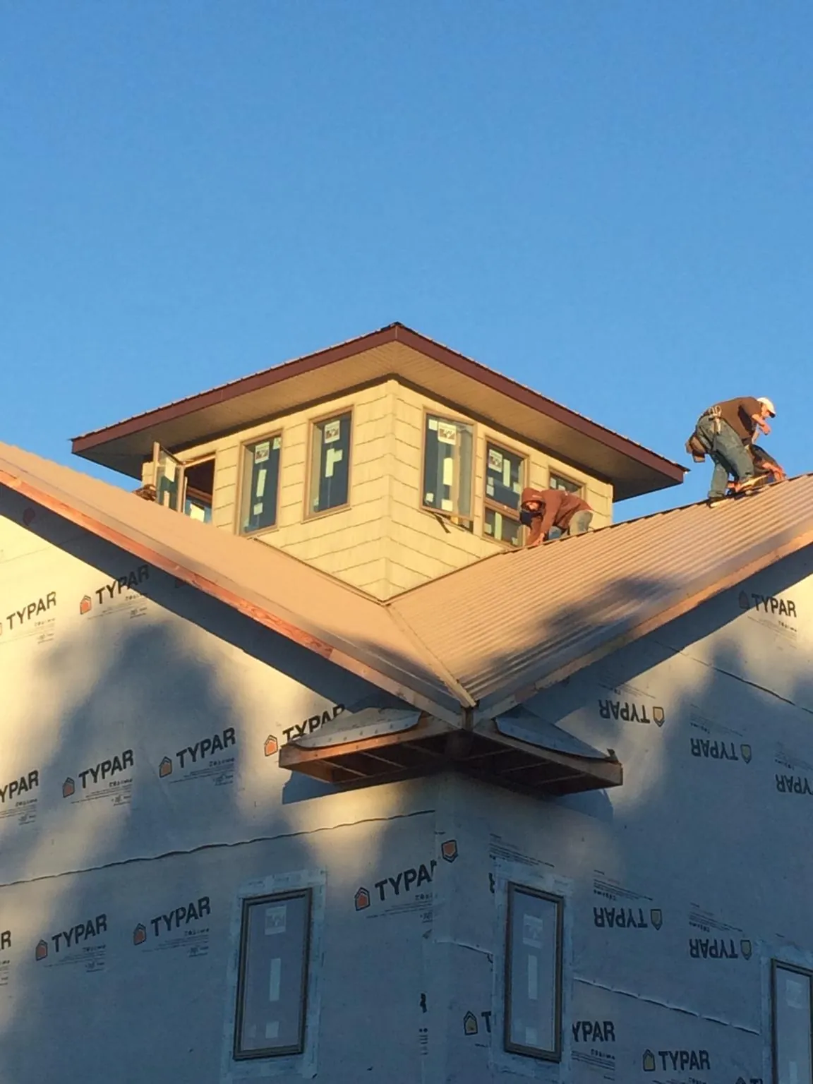 Roofers working around a rooftop cupola on a new metal roof at sunset — Roof Waterproofing in East Liberty by Roofing Brothers